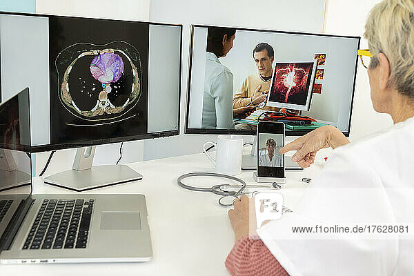 Teleconsultation between two doctors with medical images of stomachs on one of the screens.
