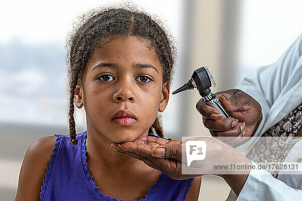 ENT physician looking into patient's ear with an instrument   Child suffereing from ear pain
