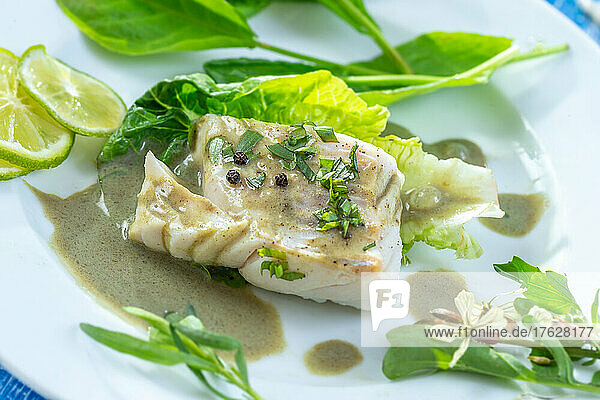 Steamed cod fillet with sorrel sauce and salad leaves.