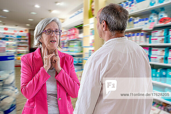 Pharmacist is talking to a senior having a sore throat.