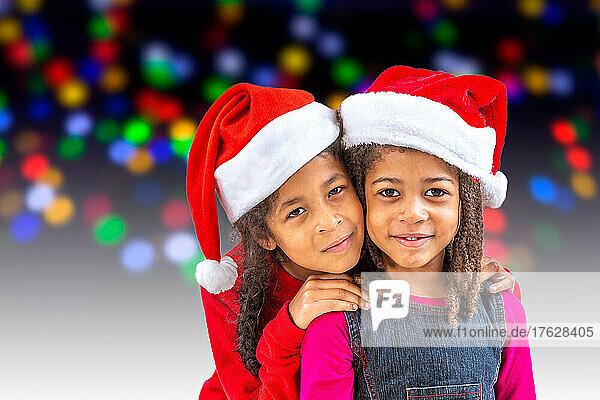 Happy little children in Santa hats against blurred festive lights. Christmas celebration