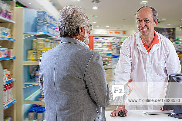 Pharmacist and senior customer discussing medications.