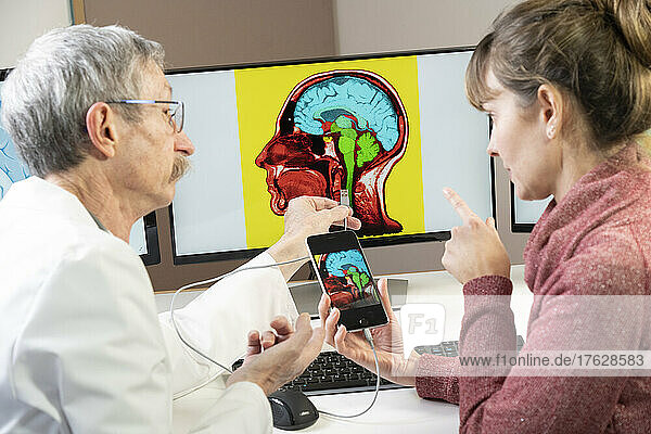 Researcher explaining to a woman how one will soon be able to pin his cell phone directly in the brain.