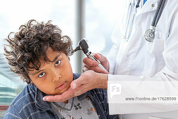 Smiling doctor examining little boy's ears at the practice