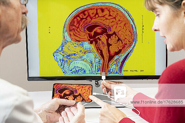 Researcher explaining to a woman how a smartphone can be connected to a brain.