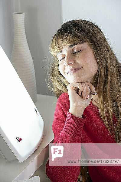 Woman sitting with her diary near a light therapy lamp.
