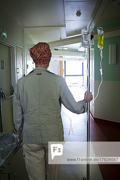 Patient in a hospital corridor moving with her chemotherapy drip.
