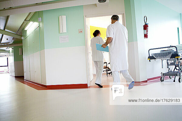 Doctor and nurse entering female patient room in hospital.
