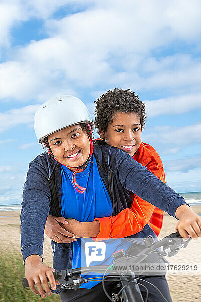 Two teens boy and girl riding bicycle on a beach way