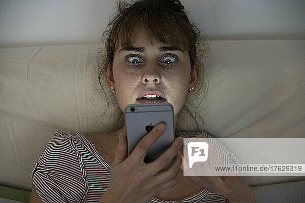 Woman at night admiring her lit smartphone. Addictive behavior.