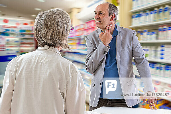 Pharmacist is talking to a men having a sore throat.