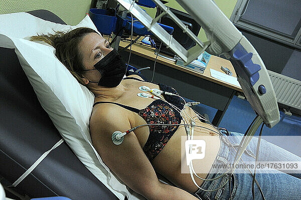 A 40-year-old woman undergoes an EKG machine to assess her heart function.