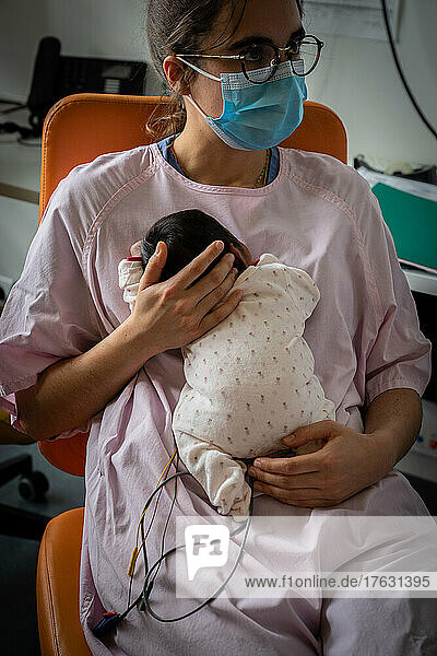 A midwife takes care of a premature baby while the mom is busy.