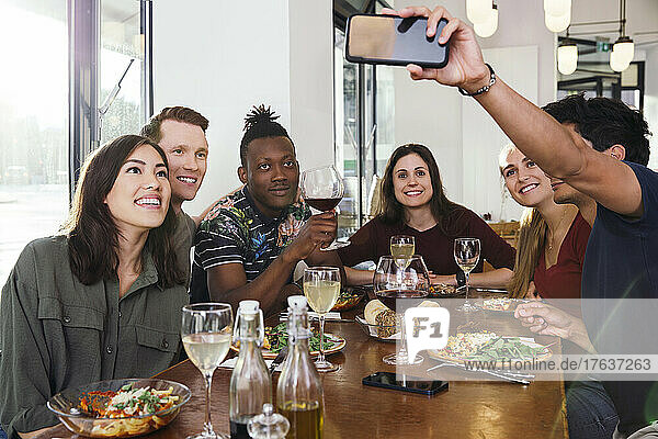 Smiling friends taking selfie in restaurant
