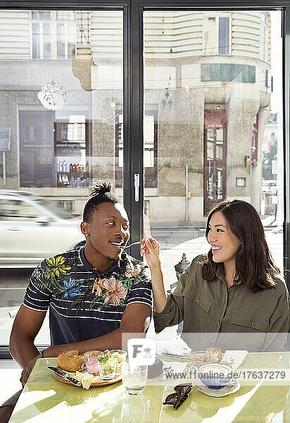 Smiling couple sharing food in restaurant