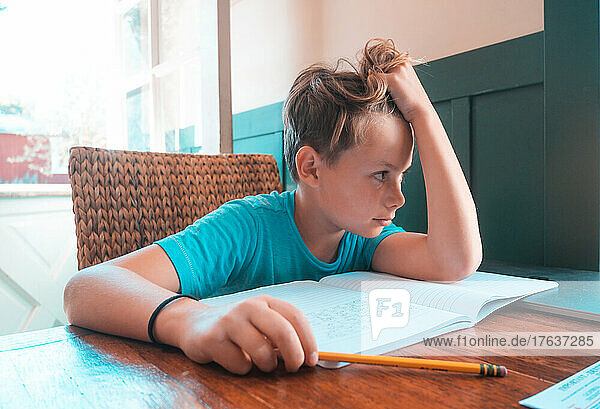 Bored boy doing homework at table