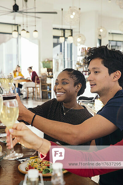 Smiling friends toasting with wine in restaurant