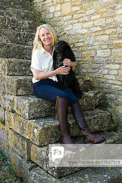 Portrait of smiling woman sitting on stone steps with dog