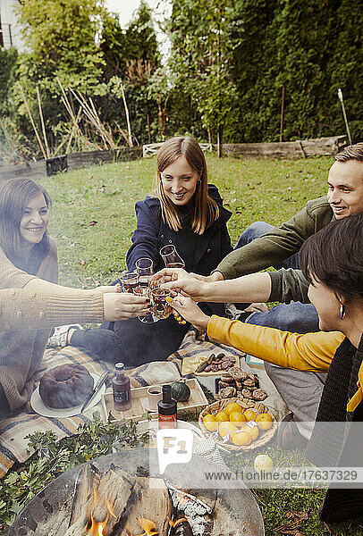 Group of friends toasting around fire pit in garden