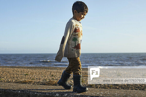 UK  Devon  Boy in oversized sweaterÊwalking on beach