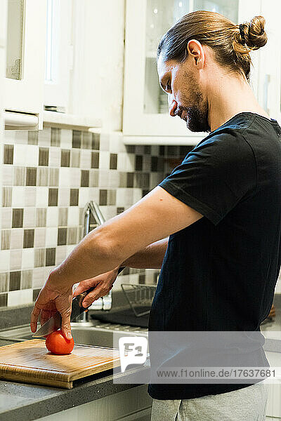 Man cutting tomato in kitchen