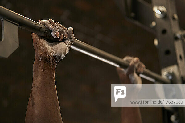 Close-up of mans hands with chalk lifting barbell in gym