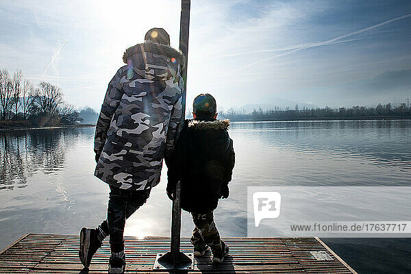 Italy  Rear view of brothers  on pier on calm lake
