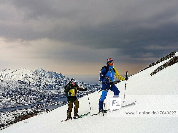 Zwei Skitourengeher im Aufstieg  bedrohliche Wolken  Insel Senja  Troms  Norwegen  Europa