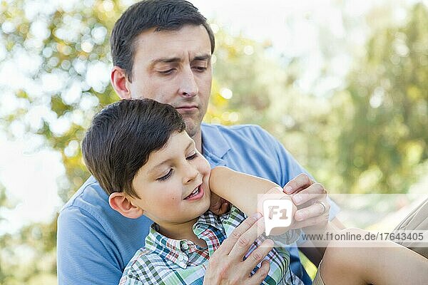 Loving father puts a bandage on the elbow of his young son in the park