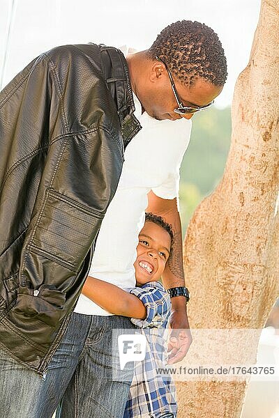 Glücklicher afroamerikanischer Vater und gemischtrassiger Sohn spielen im Park