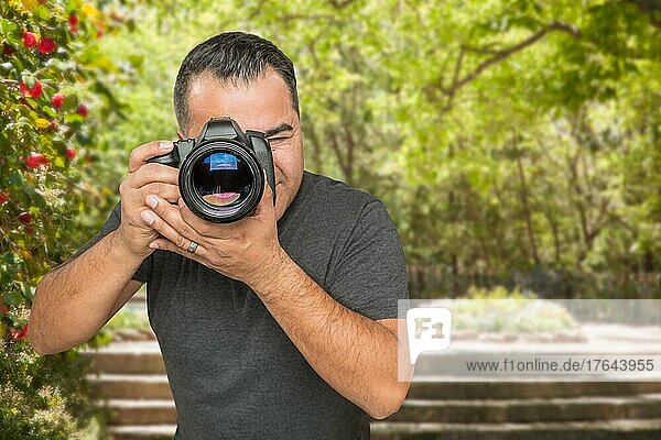 Hispanischer junger männlicher Fotograf mit DSLR-Kamera im Freien