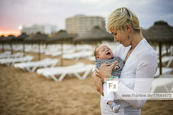 Mother with her newborn baby boy bonding at the beach in the resort by sunset  Algarve  Portugal  Europa