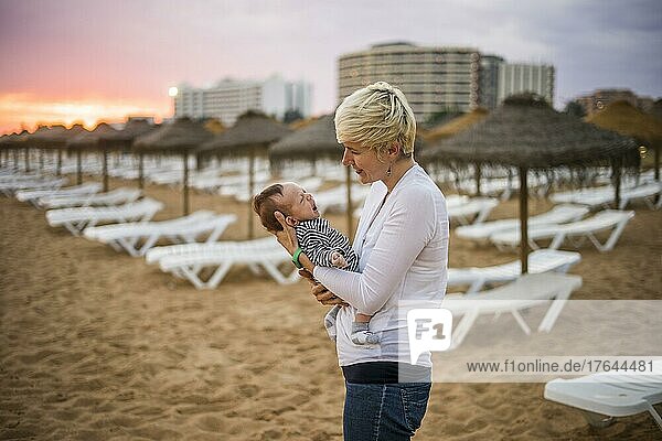 Mother with her newborn baby boy bonding at the beach in the resort by sunset  Algarve  Portugal  Europe