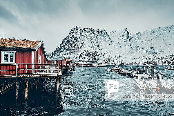 Traditional red rorbu houses in Reine fishing village in winter and pier with boats. Lofoten islands  Norway