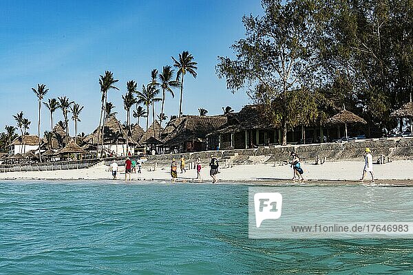 Vorne Wasser  hinten Strand vor Nungwi mit Hütten und Palmen  Passanten  Nordküste  Sansibar  Unguja  Tansania  Afrika