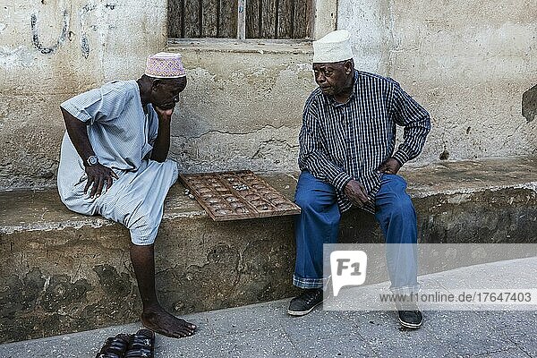 Zwei Männer spielen Bao auf einer Stufe vor dem Haus  typisches Brettspiel Bao Mancala  Stone Town  UNESCO Weltkulturerbe  Altstadt  Sansibar  Unguja  Tansania