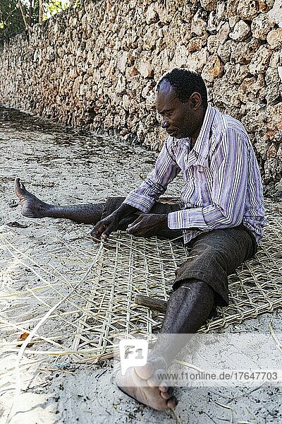 Mann flechtet eine Matte  Ostküste  Unguja  Sansibar  Tansania  Afrika