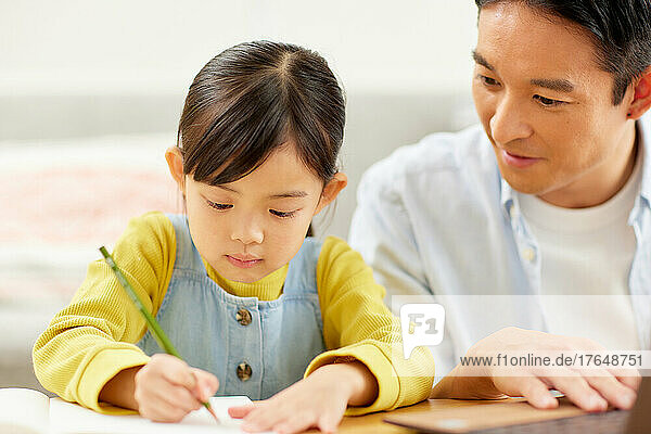 Japanese kid studying at home with her parents