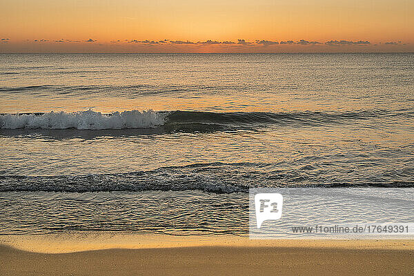 Ocean waves on beach at sunrise