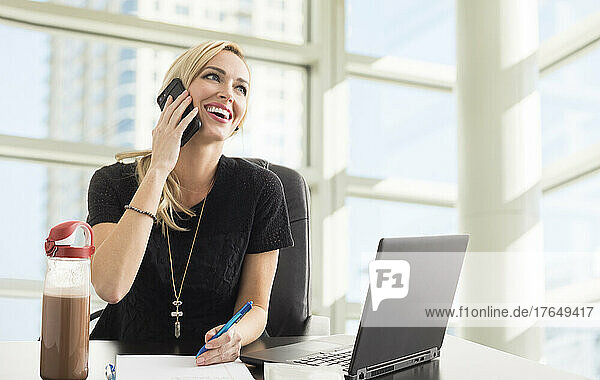 Smiling businesswoman talking on phone in office