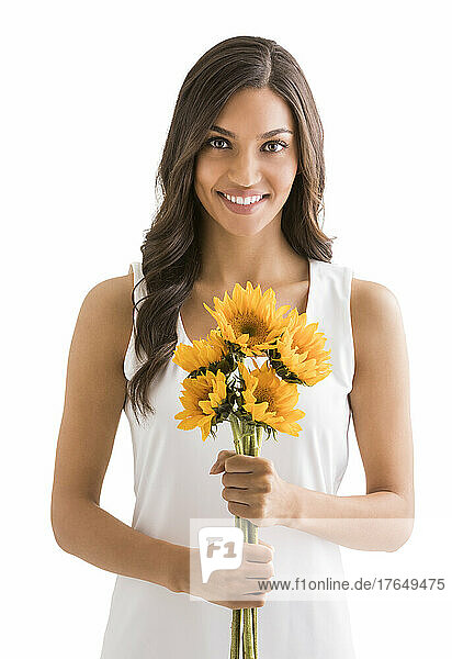 Studio portrait of smiling woman holding bunch of sunflowers