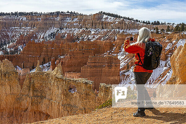 United States  Utah  Bryce Canyon National Park  Rear view of senior female hiker photographing rocks in Bryce Canyon National Park