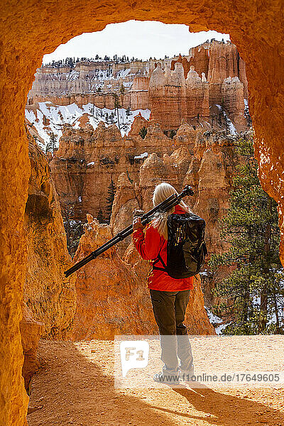 United States  Utah  Bryce Canyon National Park  Rear view of senior female hiker with backpack and tripod looking at view in Bryce Canyon National Park