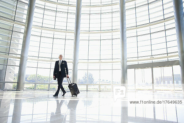 Businessman pulling luggage in lobby
