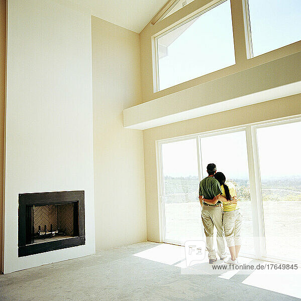 Couple embracing in living room of new home