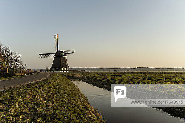 Canal by windmill on agricultural field