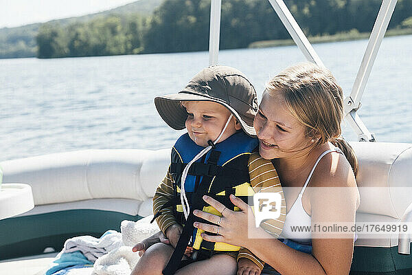 Niedlicher kleiner Junge sitzt auf dem Schoß einer Frau auf einem Flussboot