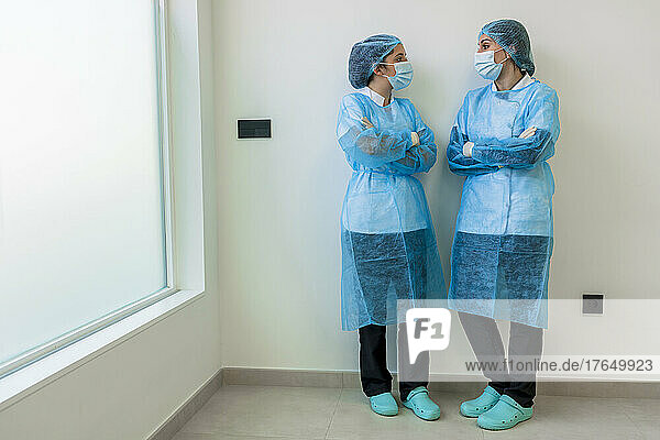 Nurses in surgery clothes standing with arms crossed in hospital