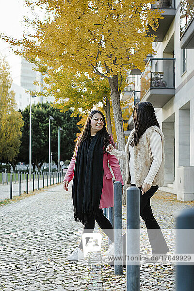 Sisters walking on footpath in front of building