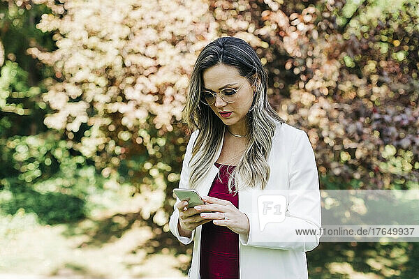Businesswoman text messaging through smart phone at park